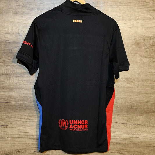 Black shirt with UNHCR ACNUR logo on a wooden surface