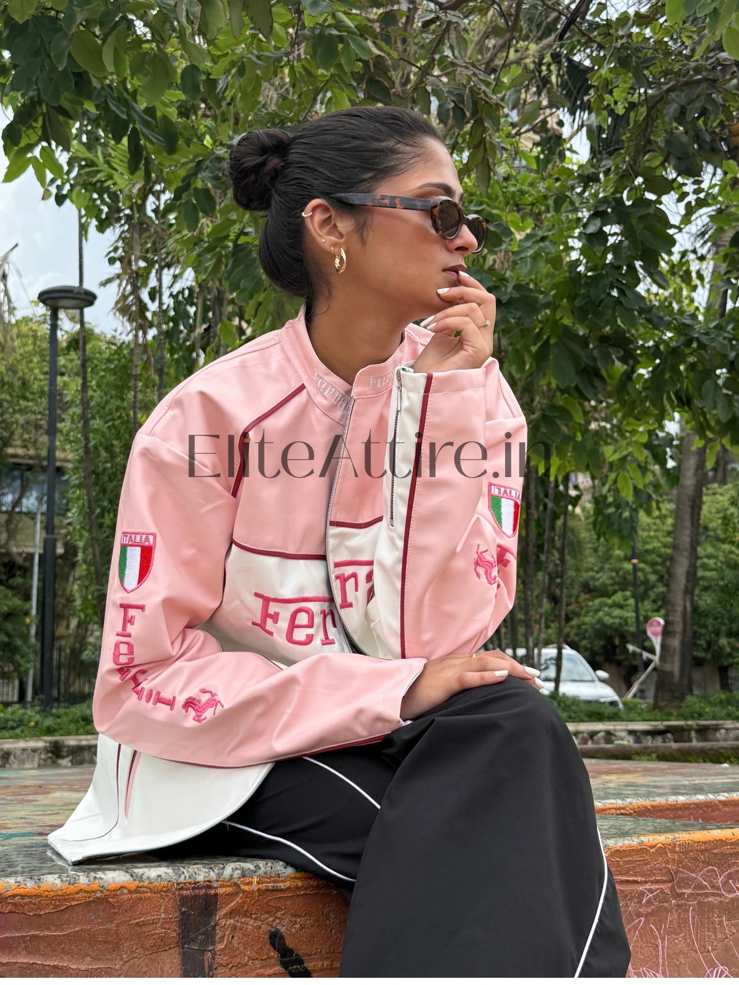 Person wearing a pink and white jacket with branding, sitting outdoors.