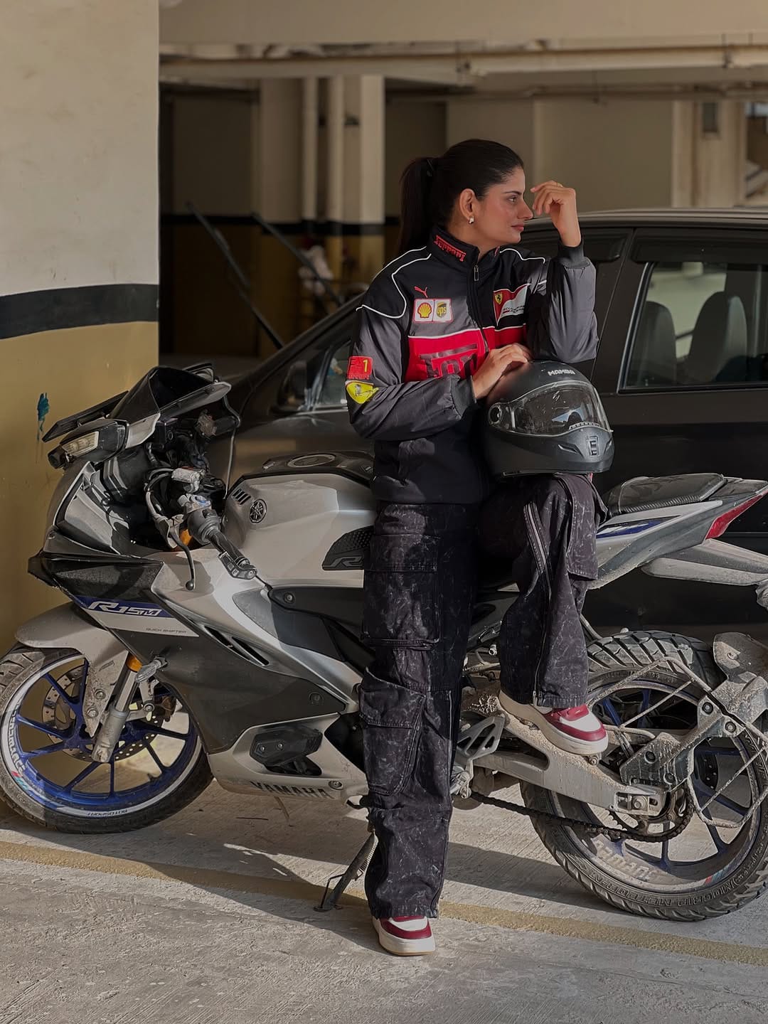 Person standing next to a motorcycle and car in a parking garage