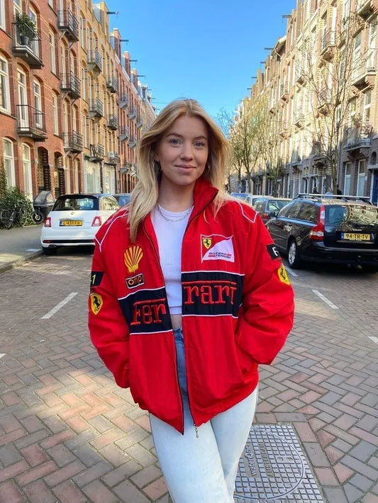 Person wearing a red Ferrari jacket on a street with buildings and cars in the background