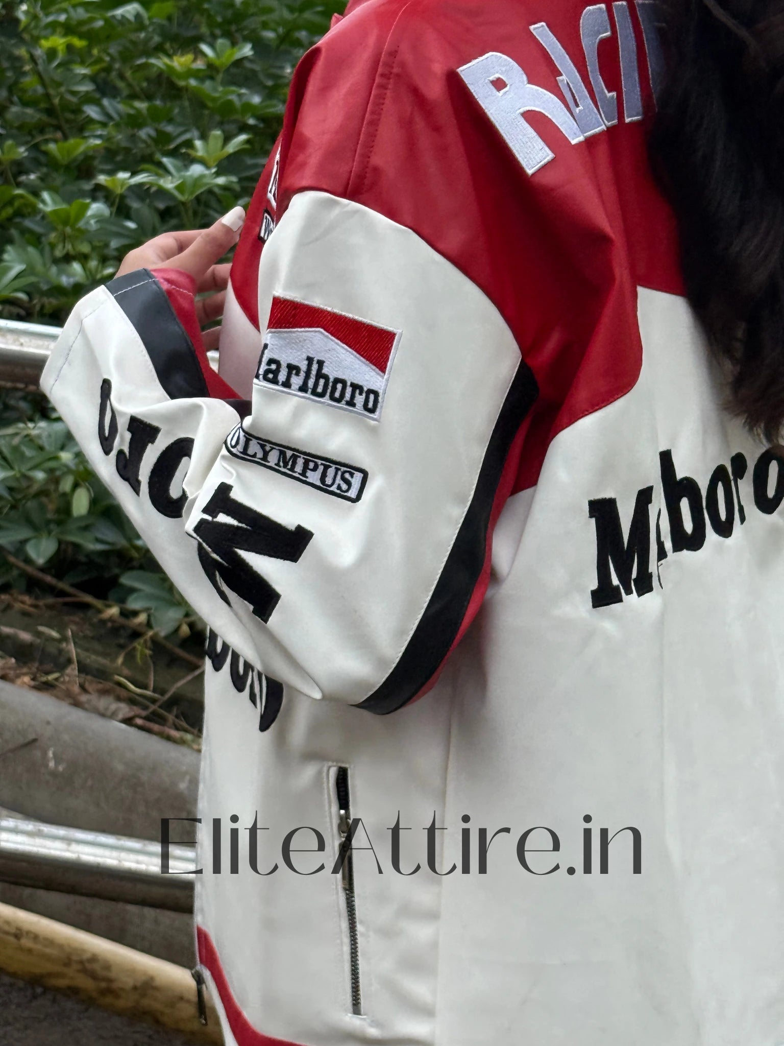 White racing jacket with red and black accents featuring various logos, worn by a person.