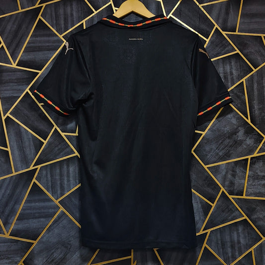 Black t-shirt on a hanger against a geometric patterned wall.