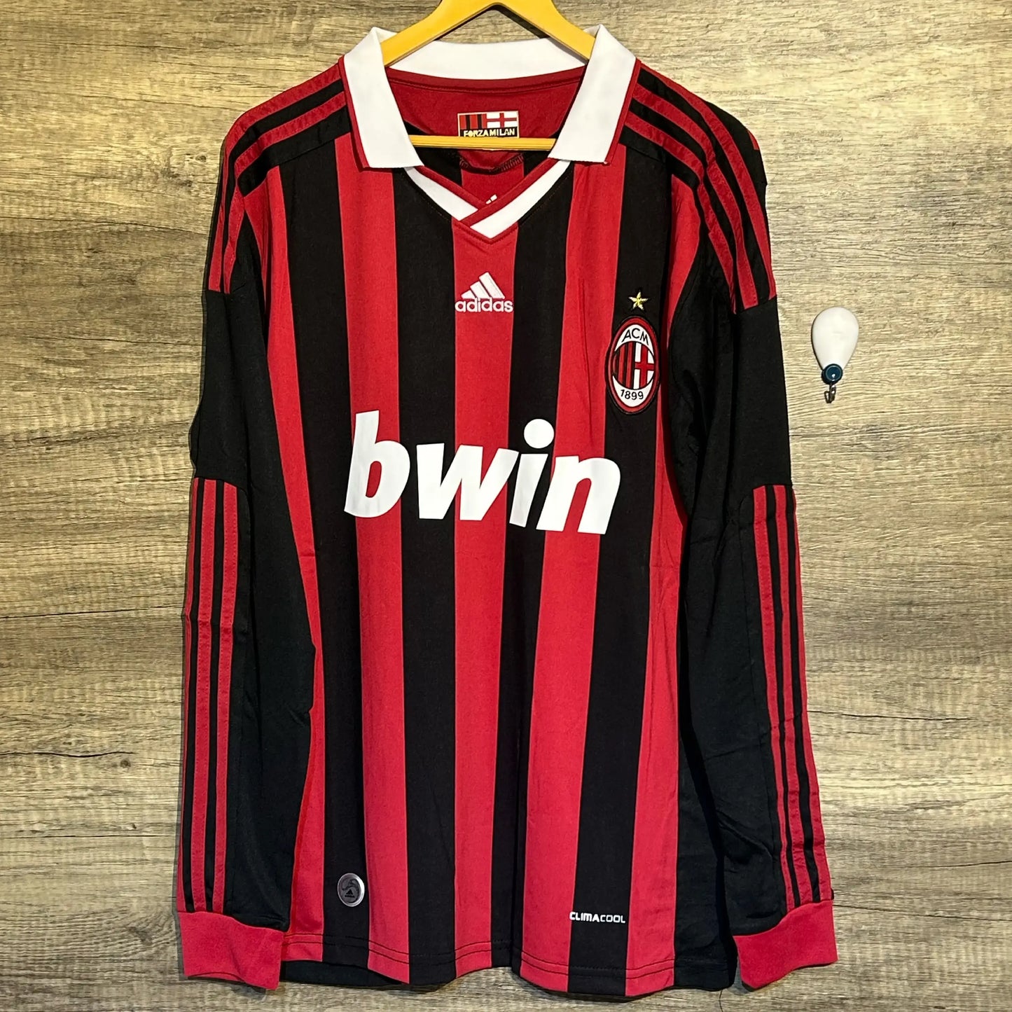 Red and black striped sports jersey with Adidas and Bwin logos on a wooden background
