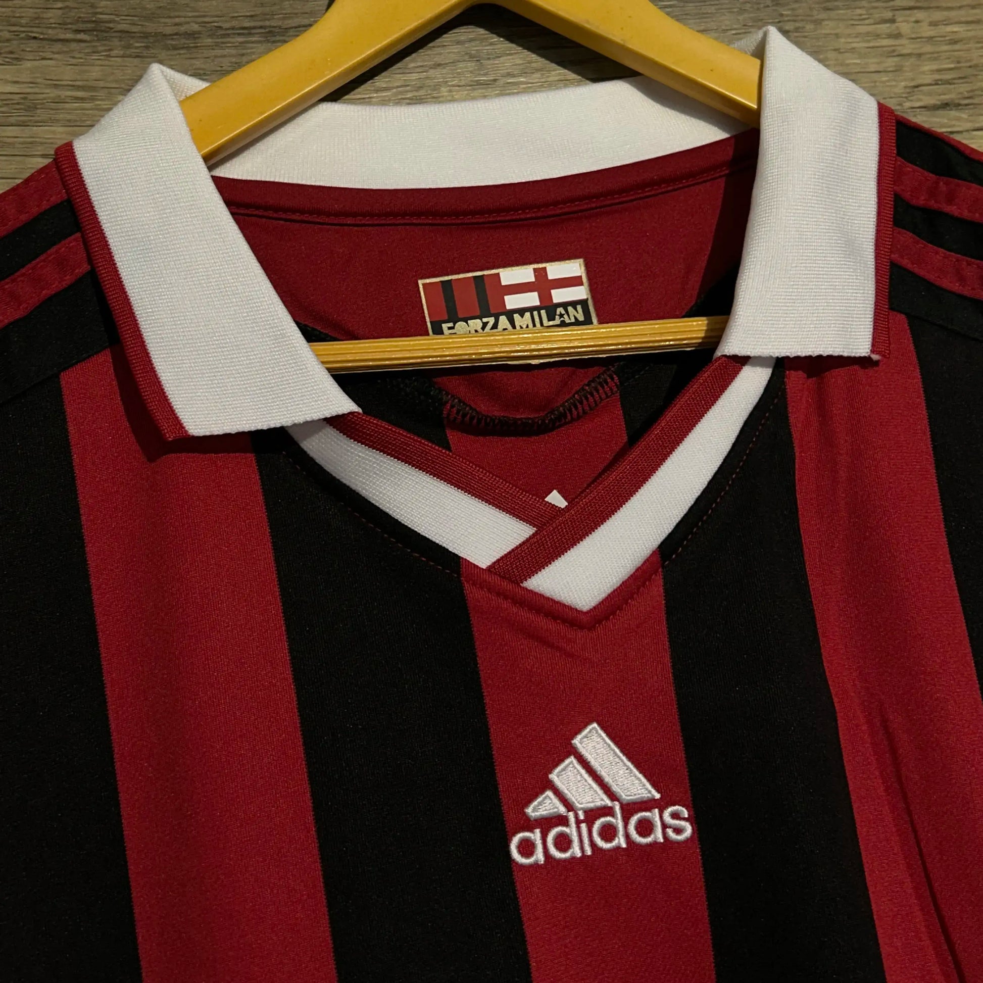 Red and black striped sports jersey with Adidas logo on a hanger