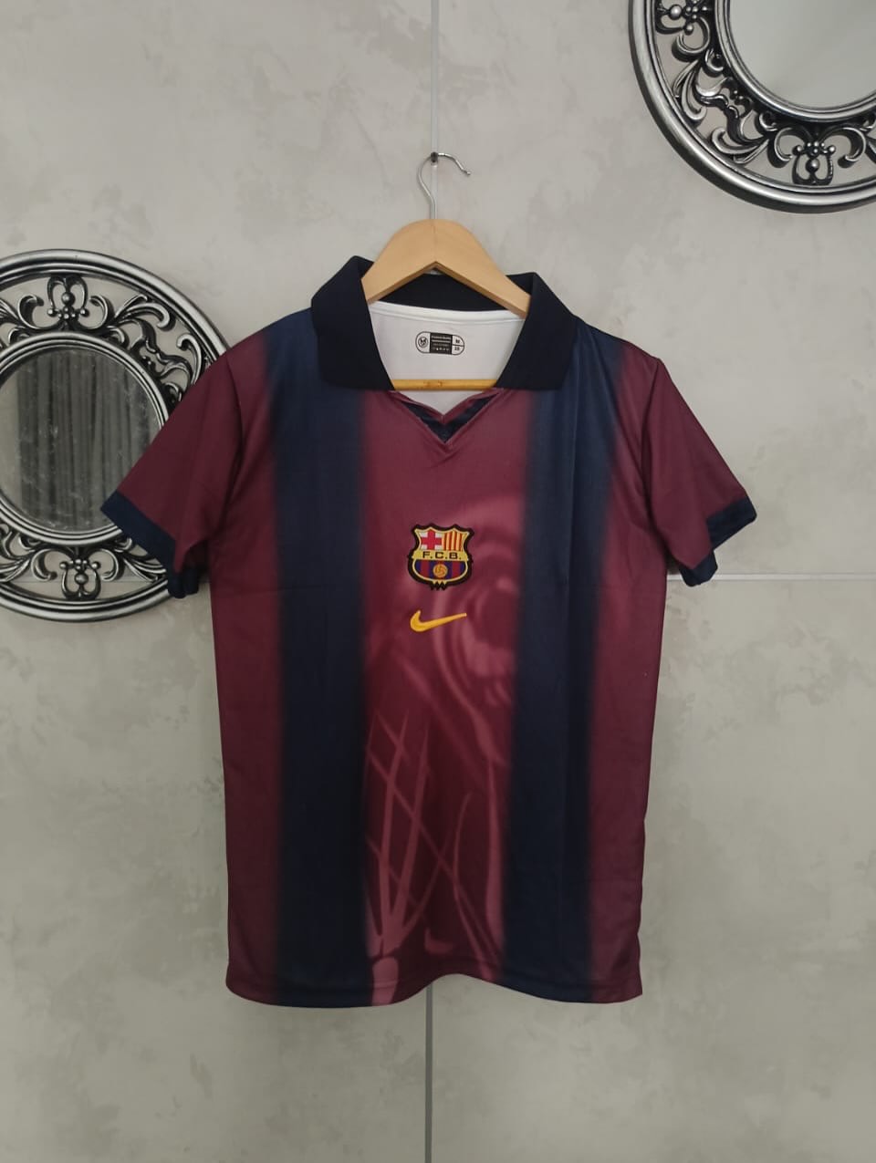 Maroon and navy sports jersey with Nike logo on a hanger against a light gray wall.