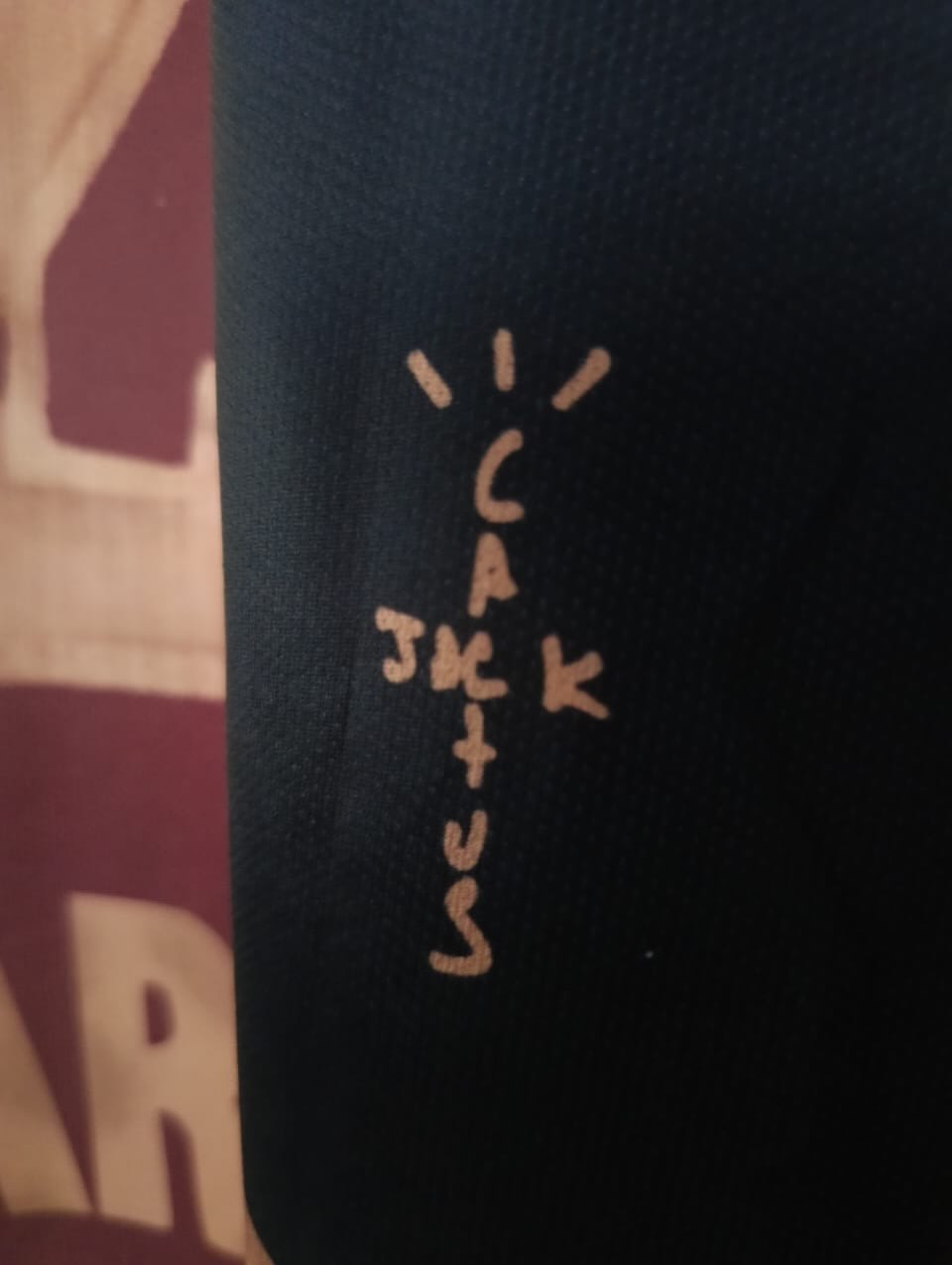 Text 'I LUV JK' embroidered on a dark fabric background