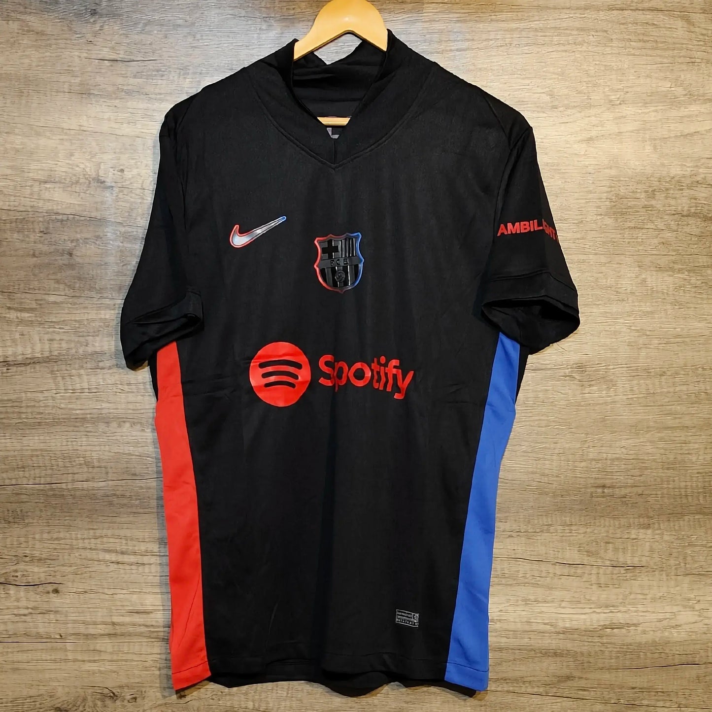 Black sports jersey with multiple logos on a wooden surface