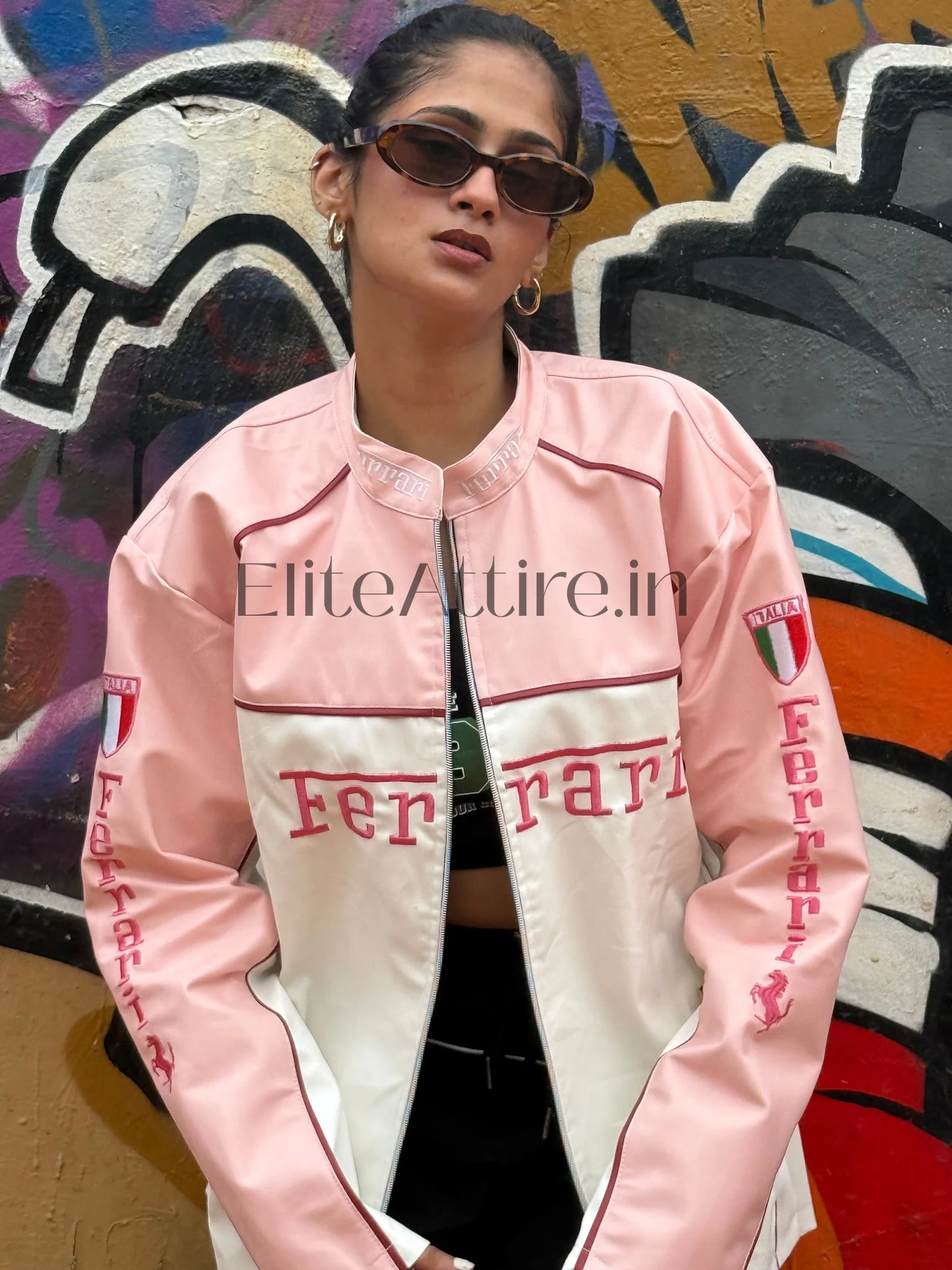 Person wearing a pink and white Ferrari jacket in front of a colorful mural.