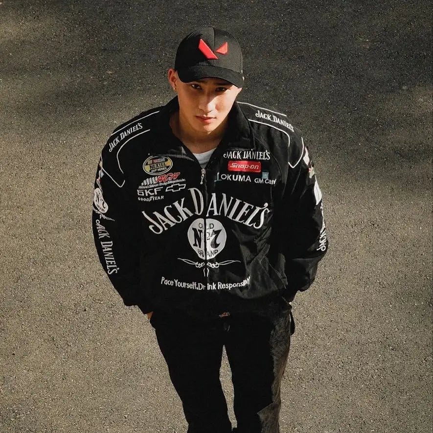 Person wearing a black 'Jack Daniel's' jacket and cap on a dark background