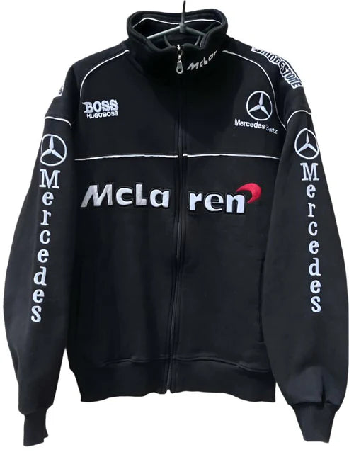 A black McLaren Mercedes racing jacket with the logos of both brands on the sleeves and the back. The jacket is displayed on a hanger.