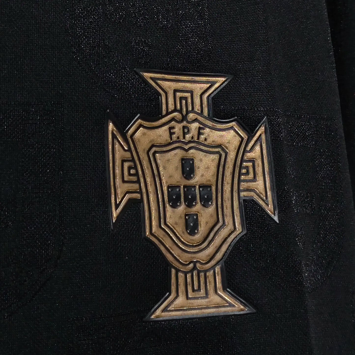 Bronze cross emblem with 'F.P.F.' on a black background